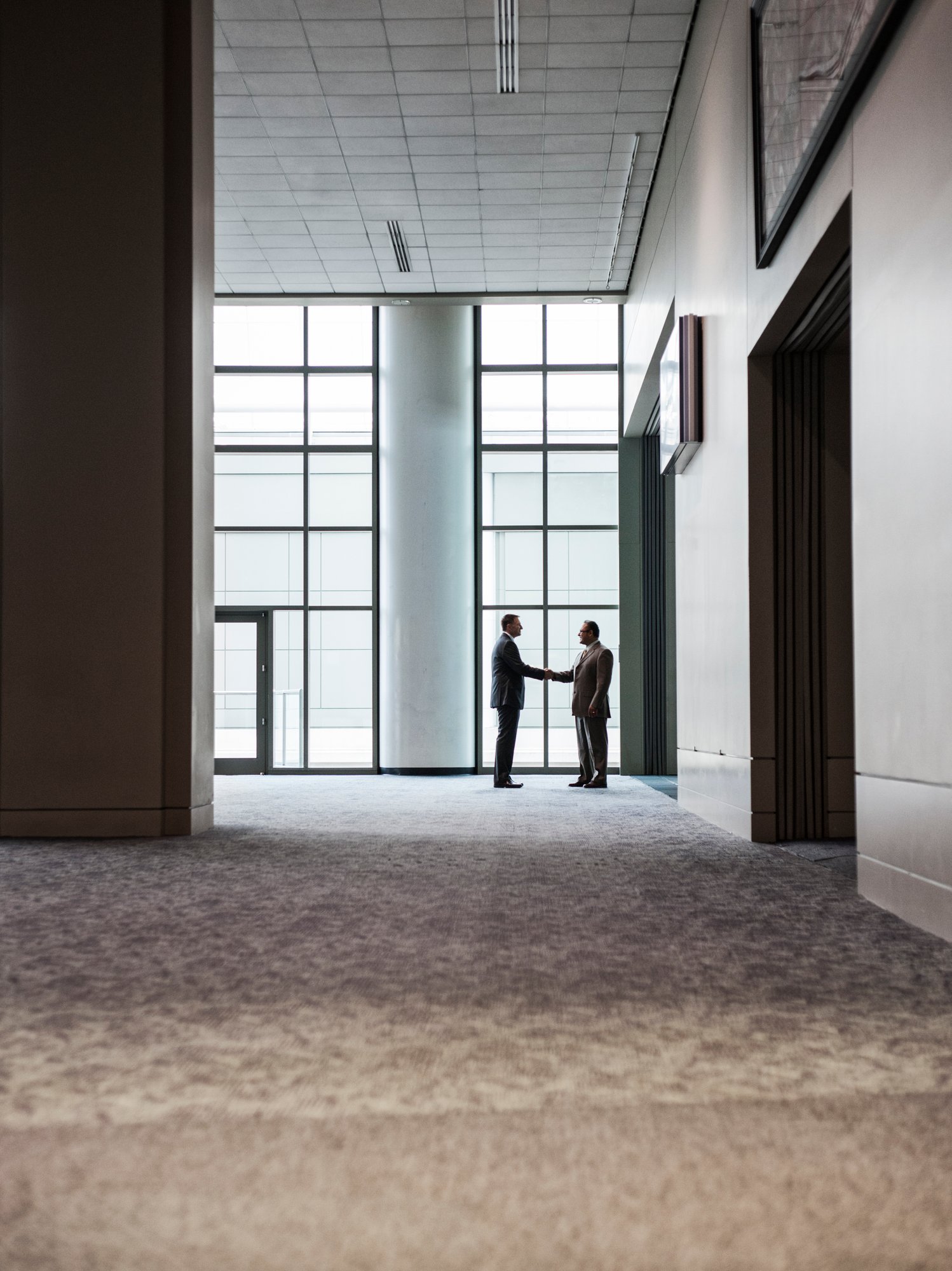 two-businessmen-silhouetted-and-shaking-hands-in-f-2023-11-27-05-31-58-utc